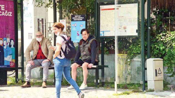 Kaya Çilingiroğlu wyświetlana bez maski na przystanku autobusowym.